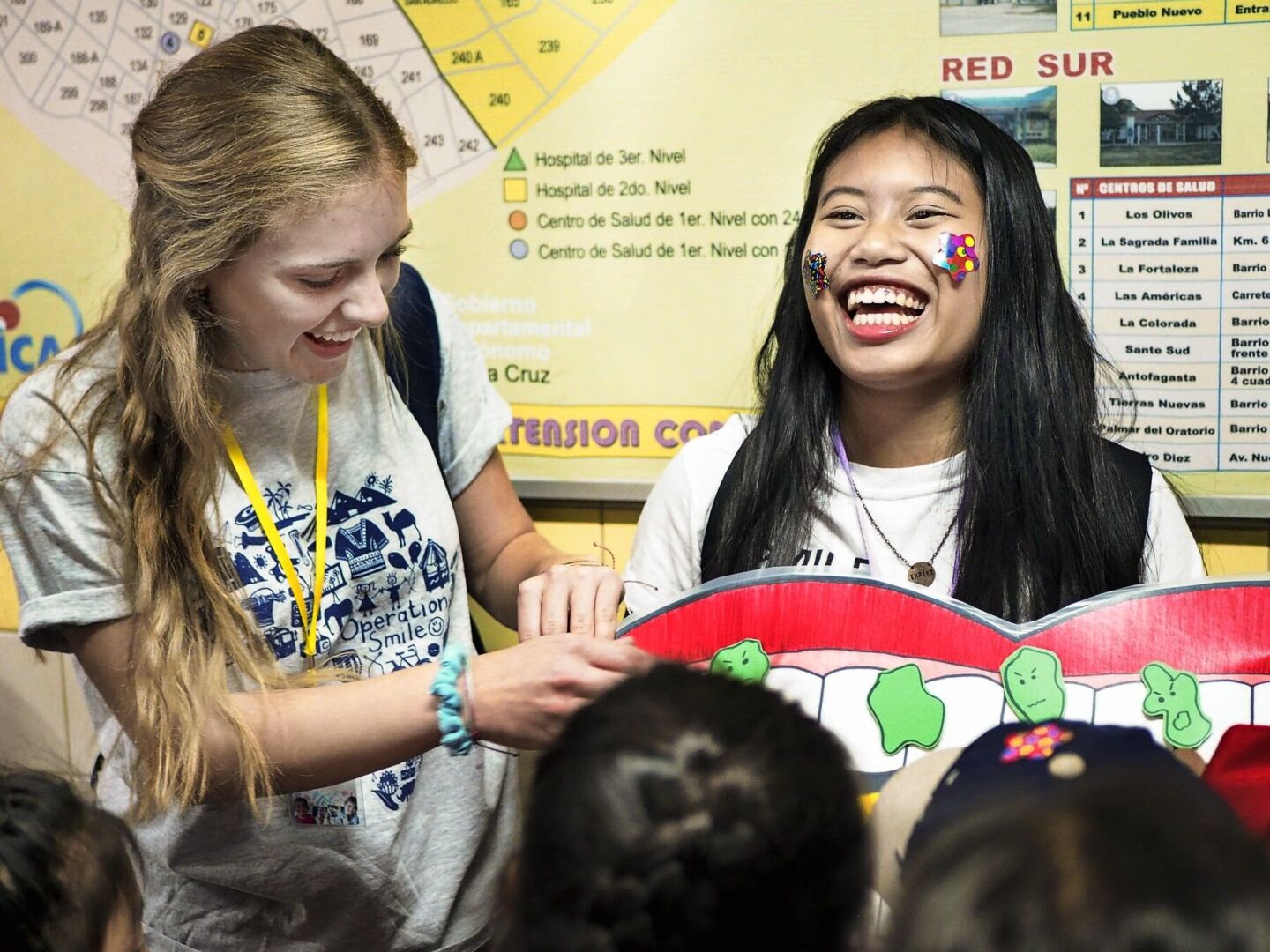 Operation Smile student volunteers laugh while sharing information about oral care.