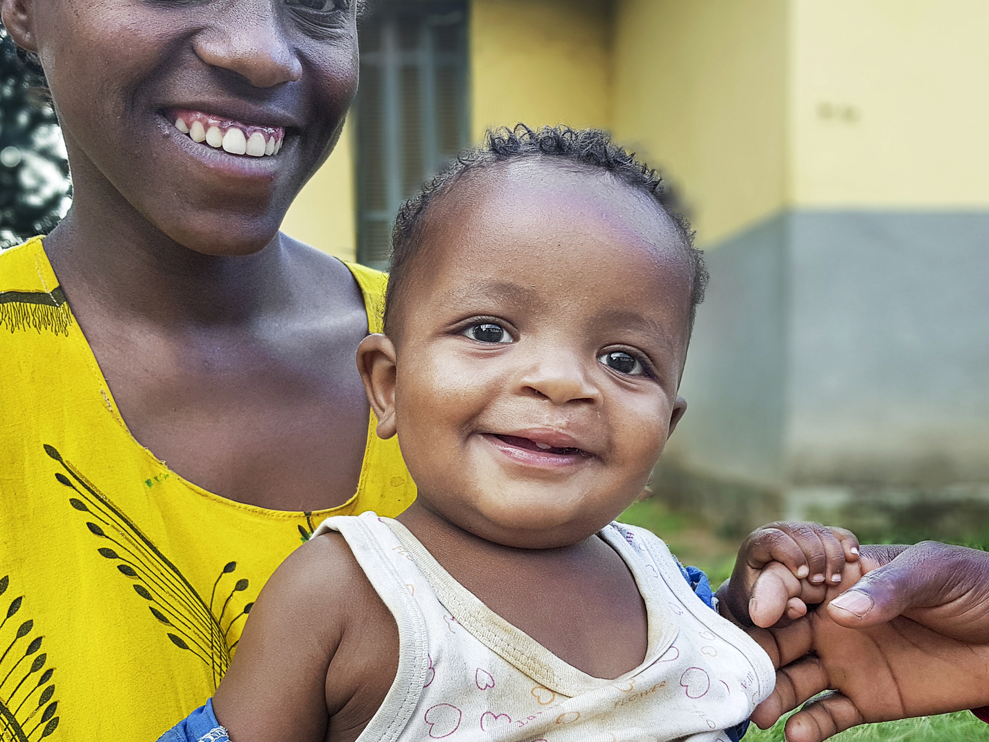 Tesfasihu sits with her 2-year-old son, Ashenafi, as he holds his father’s finger.