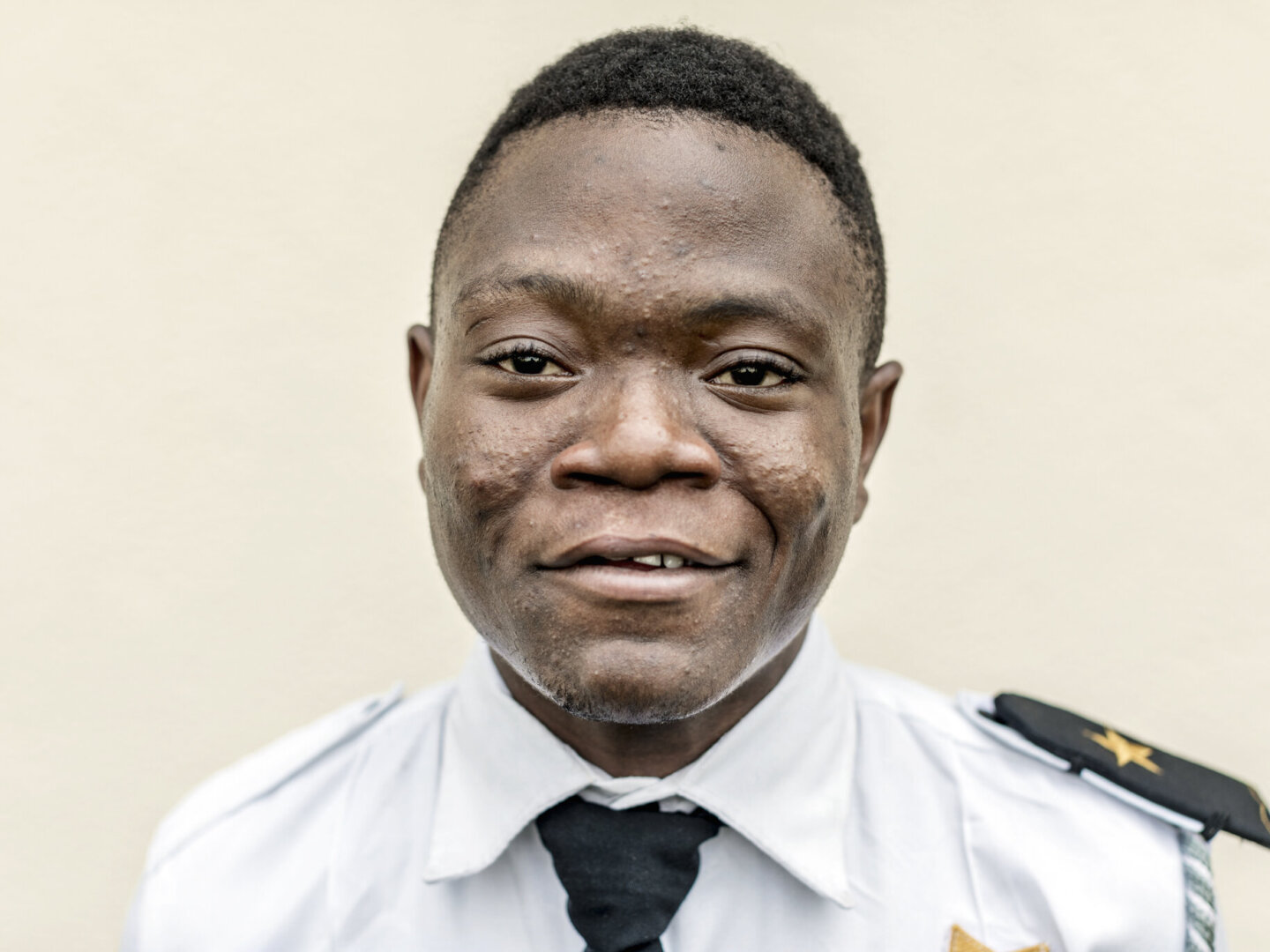 Samuel smiles proudly in his security guard uniform.