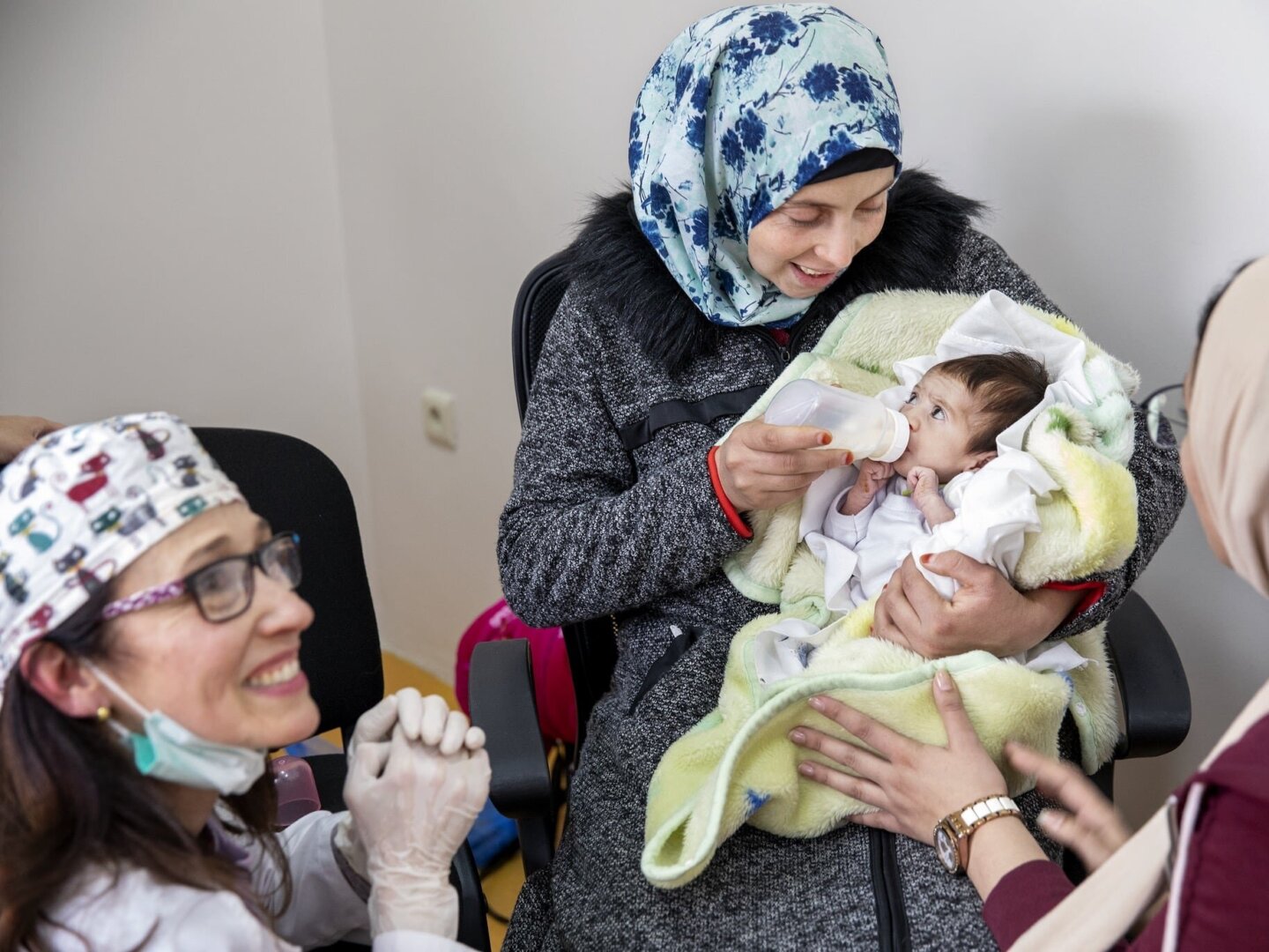 Volunteer dentist Dr. Teresita Pannaci of Venezuela, left, observes as Janat is fed by her mom while testing out her new feeding plate.