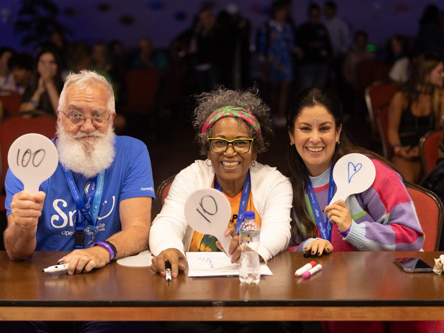 Three individuals smile during ISLC 2023.