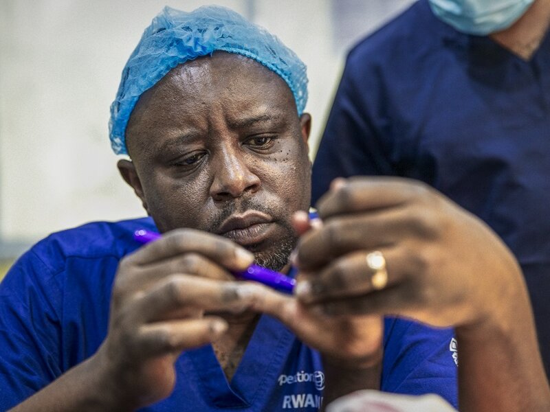 Surgeon Faustin Ntirenganya examines a patient's hand during a surgical program in Rwanda.