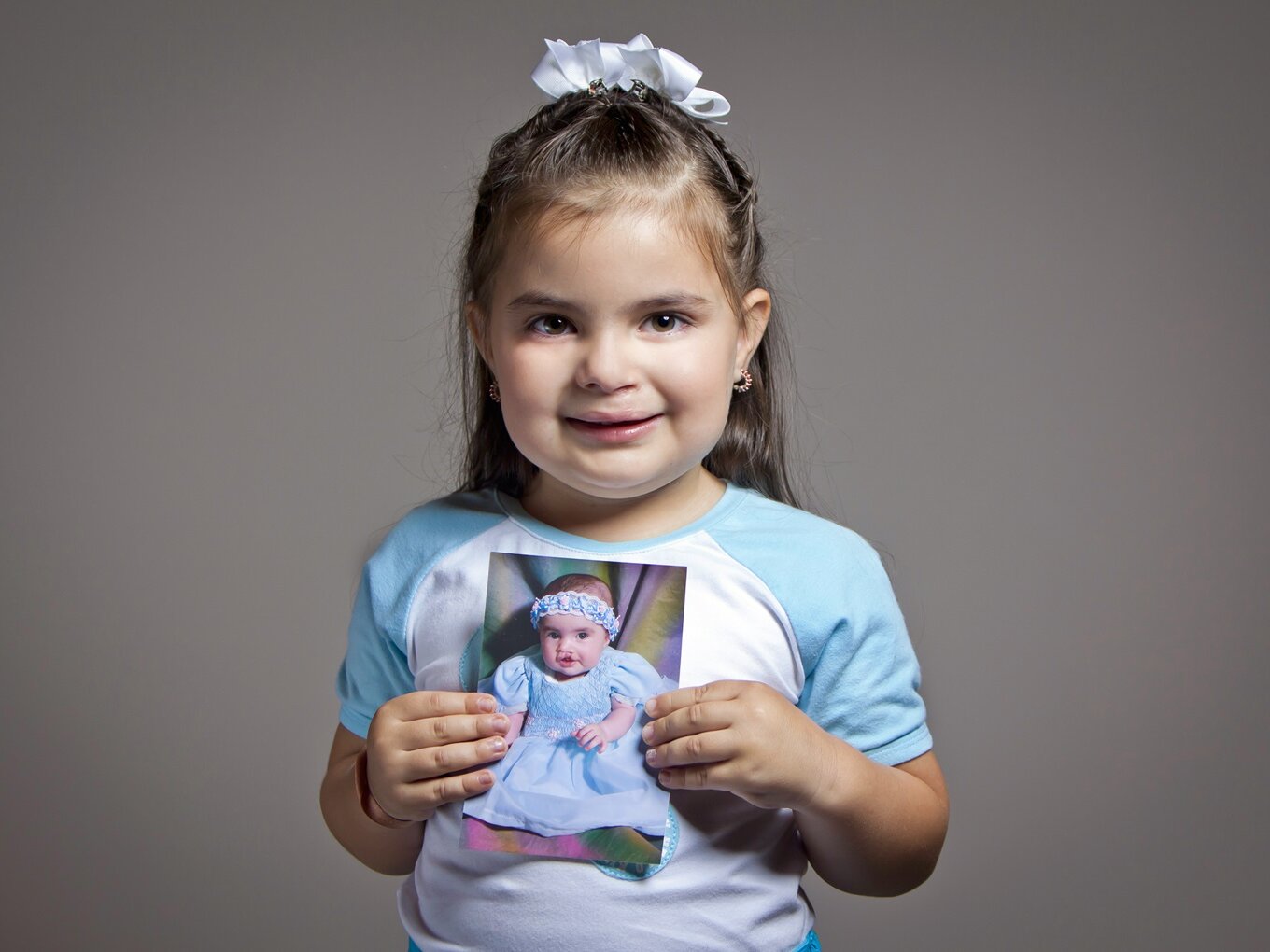 Stephanie holds her before photo while smiling for the camera.