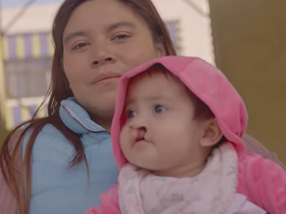 Camila and Mateo's moms hold them while at a surgical program in Puebla, Mexico.