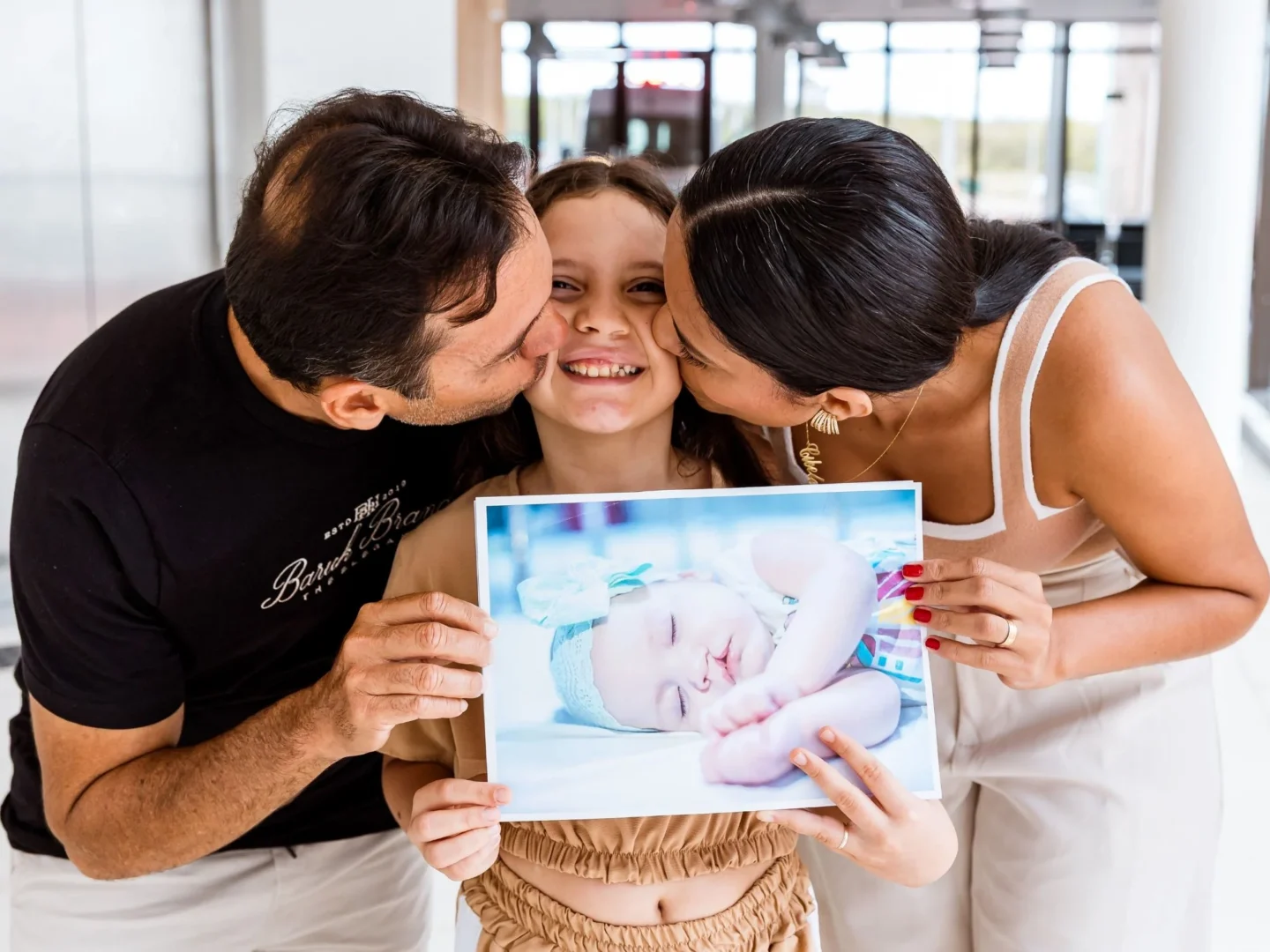 Patient Anna Clara poses with her patients and her before photo. Your gift can support patients like her.