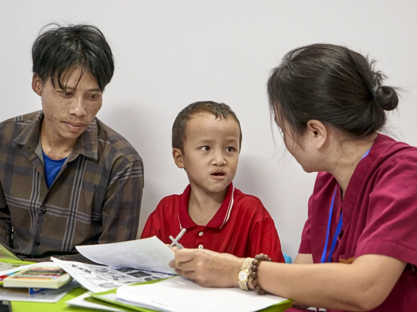Vien and his father sit with a health care provider for speech therapy.